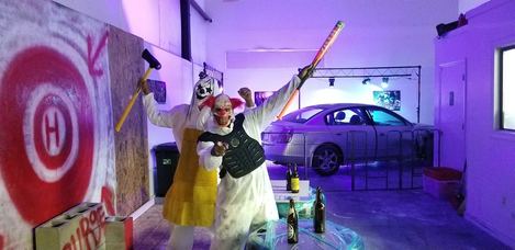 Photograph of two angry clowns holding an axe and a bat at the House of Purge smash room.